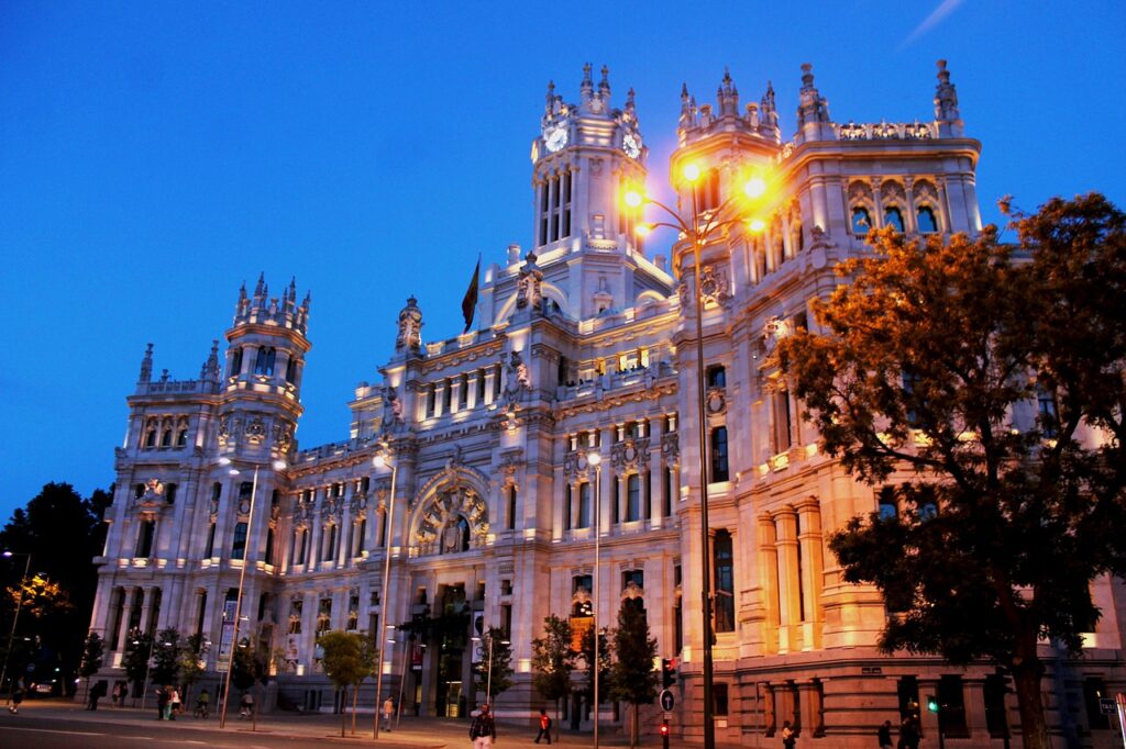 Fuente de Cibeles iluminada de noche con el Palacio de Cibeles al fondo.