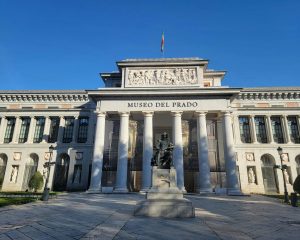 Prado Museum's iconic facade under clear blue skies in Madrid, Spain.